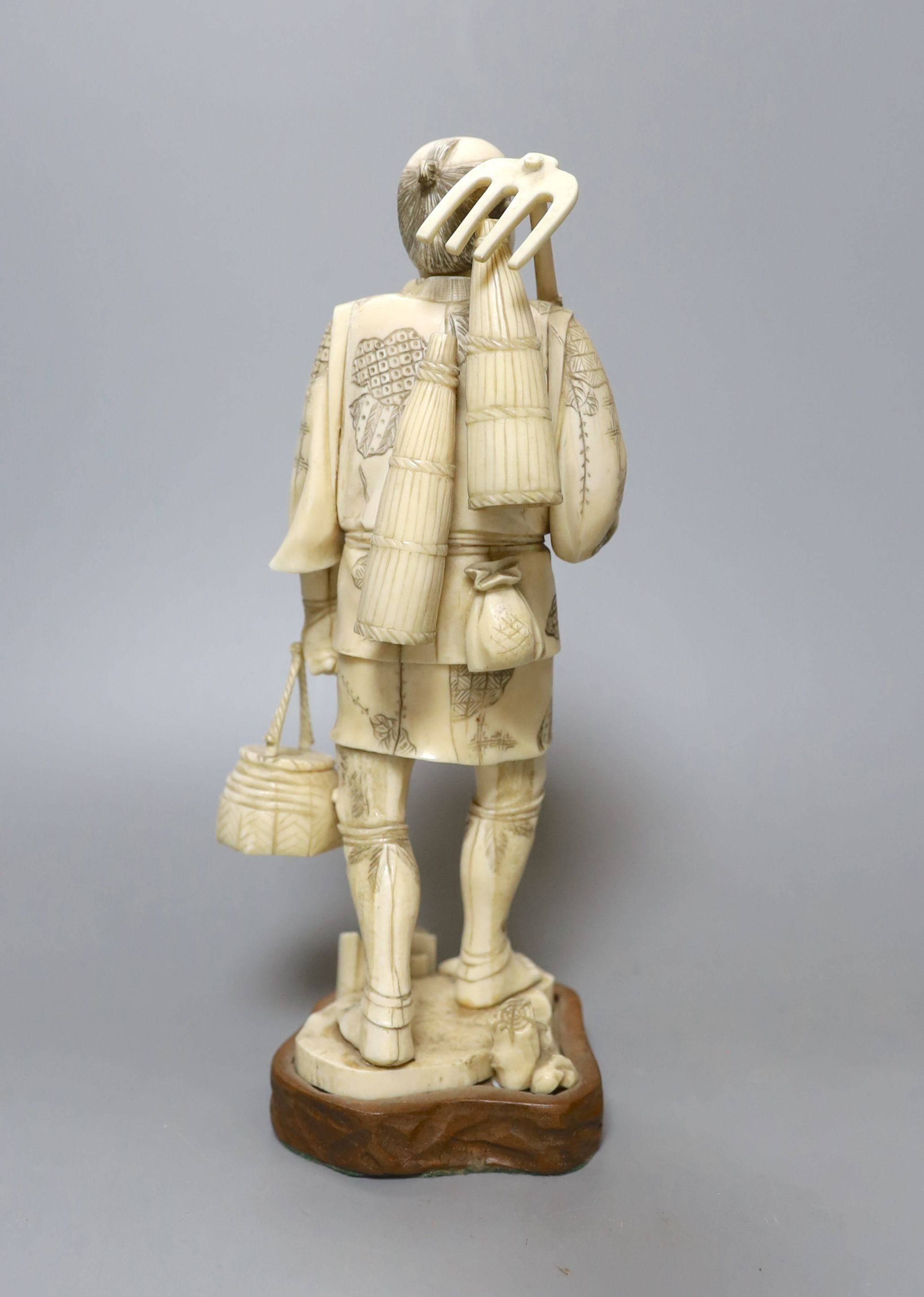 A Japanese carved and engraved ivory figure of a farmer, Meiji-period, on plinth, 25cm